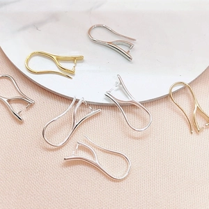 Chiusure per orecchini fai-da-te oro e argento su piatto bianco con sfondo in tessuto rosa