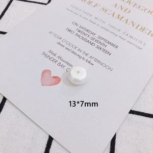Detail shot of a 13x7mm pearlescent white flat round bead with central hole for DIY jewelry