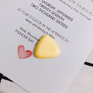 Detailed macro shot of a smooth light yellow triangular resin accessory on white card