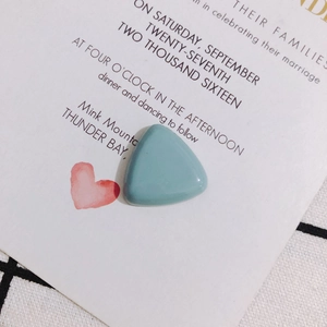 Close-up of a light blue triangular resin charm for DIY accessories on a white card