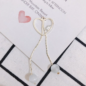 Détail d'un pendentif cœur doré avec pampilles, zircon et perles œil-de-chat