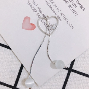 Détail de boucle d'oreille cœur argenté avec perles œil de chat et zircons brillants