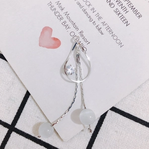 Détail d'une boucle d'oreille pompon argentée avec cadre goutte, perles opale et zircon