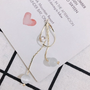Détail de boucles d'oreilles longues dorées avec perles œil-de-chat et cristaux en goutte
