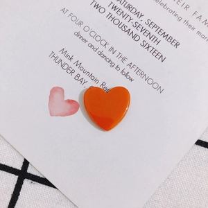 Gros plan sur un pendentif en acrylique orange vif en forme de cœur poli et brillant