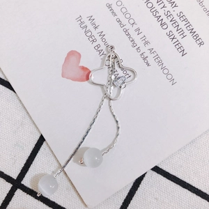 Détail d'un pendentif trèfle argenté avec perles œil de chat et longues chaînes