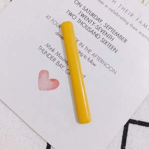 Detalle macro de un pasador de pelo largo de acrílico amarillo brillante en tarjeta
