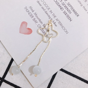 Détail de boucle d'oreille papillon doré avec chaînes à franges et perles œil-de-chat