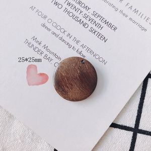 Macro detail of a 25mm round dark brown wooden pendant showing natural wood grain texture