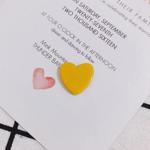 Macro d'un charme cœur en acrylique jaune sur une carte de mariage pour bijoux DIY