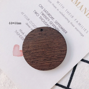 Detail of 44x44mm round coffee wood pendant with natural grain and pre-drilled hole