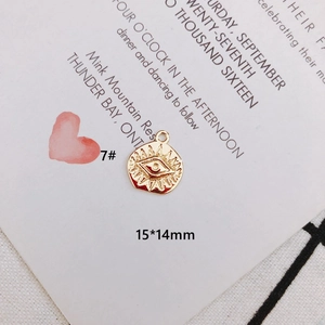 Detailed view of evil eye gold charm with textured center and size 15x14mm measurements