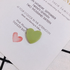 Détail macro de pendentif cœur en acrylique vert clair sur carte d'invitation chic