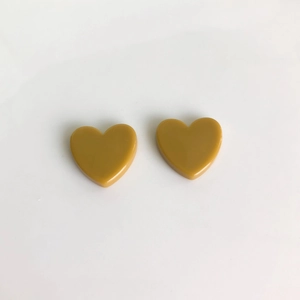 Détail de boucles d'oreilles cœur en acrylique jaune moutarde pour la création de bijoux