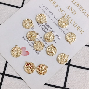 Detailed view of 18K gold plated zodiac charms with intricate embossed craftsmanship