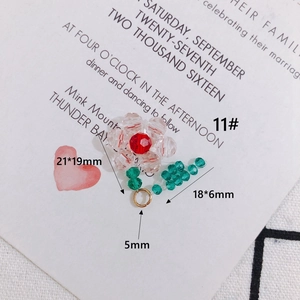 Dettaglio del ciondolo a fiore in vetro cristallo rosa intrecciato con cuore rosso e foglie