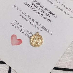 Macro shot of gold-plated 18K Gemini zodiac relief pendant with vintage serrated edges