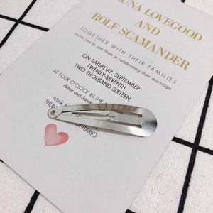 Close-up of a silver teardrop snap hair clip on a white decorative card background