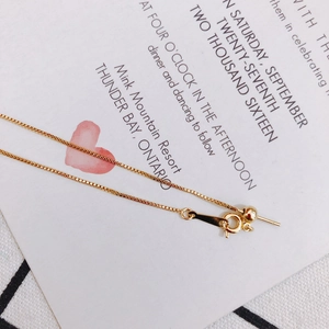 Detailed macro of gold plated box chain bracelet with adjustable bead and pin connector