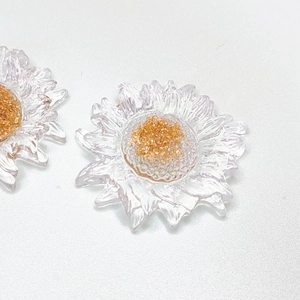 Close-up of resin daisy flower charms with gold glitter center for DIY jewelry making