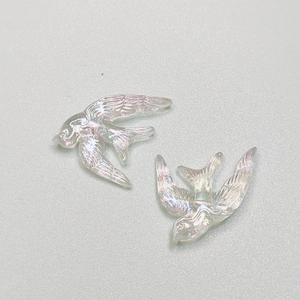 Macro shot of iridescent resin swallow charms with detailed feather texture for DIY jewelry