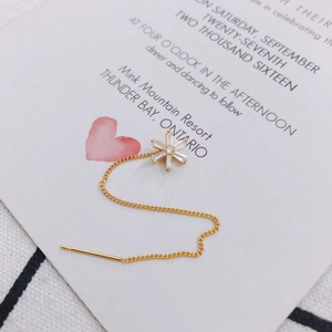 Detailansicht eines goldenen Durchziehohrrings mit Kristallblüten und langer Kette