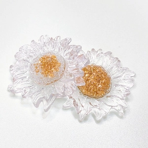 Detailed close-up of transparent resin sunflower charms with golden textured centers