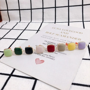 Macro view of colorful square enamel charms with gold trim for DIY jewelry making