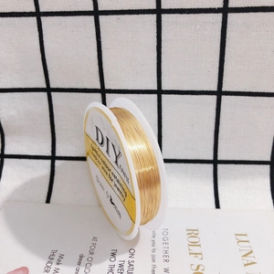 Macro detail of high-luster gold-plated copper wire on a spool for fine jewelry making