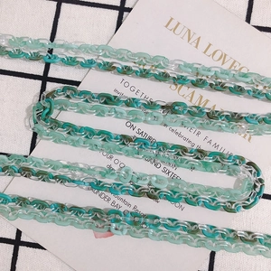 Detail of green and transparent acrylic chain links on checkered background