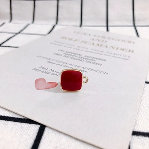 Close-up of a square red enamel pendant charm with gold metal trim for DIY jewelry making