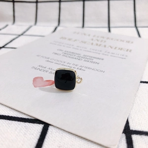 Macro detail of a square black enamel earring charm with golden frame for DIY jewelry