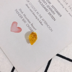 Macro shot of a yellow resin lemon charm on a white decorative card for DIY crafts