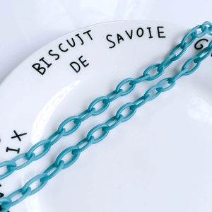 Détail d'une chaîne à maillons en résine bleu clair pour bijoux DIY sur une assiette blanche