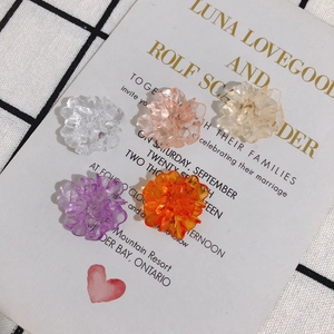 Translucent resin flower charms in five colors for DIY jewelry making on grid background