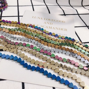 Macro view of heart-shaped hematite beads in gold, silver, and rainbow colors for jewelry DIY