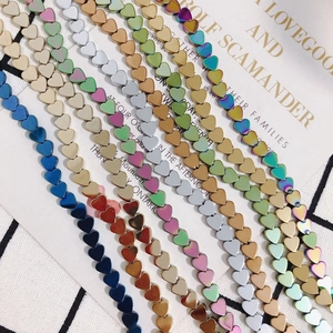 Multiple colors of heart-shaped hematite beads on a decorative background for jewelry