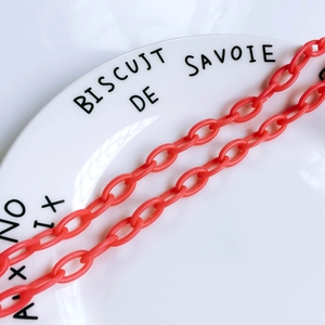 Gros plan de maillons de chaîne en résine orange corail sur assiette pour bijoux DIY