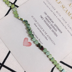 Detailed macro view of iridescent green heart beads on elegant black and white checkered fabric