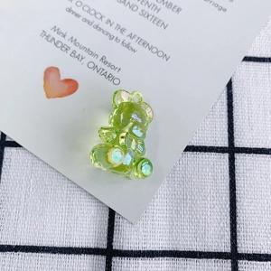 Close-up of a light green translucent teddy bear pendant with iridescent AB coating