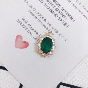 Vue détaillée d'un pendentif ovale en émeraude verte avec monture dorée et zircons blancs