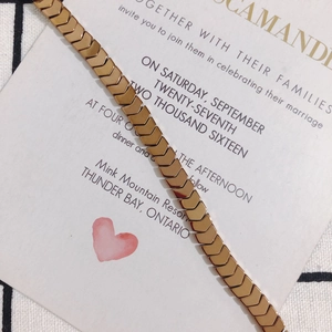 Close-up of golden chevron chain links on a wedding invitation and checkered fabric