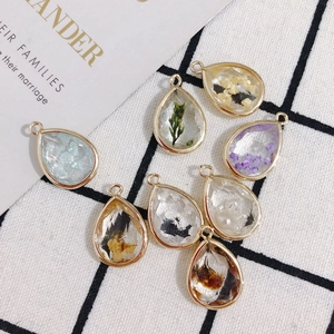 Detailed view of teardrop pendants with dried flowers and gold foil for DIY jewelry