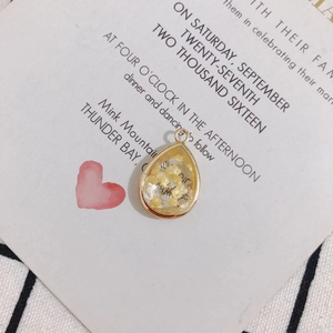 Close-up of teardrop resin pendant with dried yellow flowers and gold metal trim