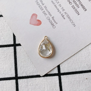 Macro view of teardrop faceted pendant with golden edges and purple dried flowers