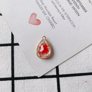 Detailed view of teardrop copper pendant with red dried flowers and golden edges