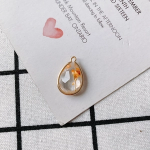 Macro shot of waterdrop resin pendant with orange dried flower and gold metal edging