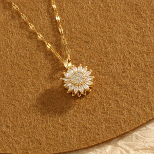Collana rotante a girasole dorata con zirconi cubici su sfondo in feltro marrone