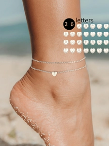 Detailansicht der silbernen Doppelfußkette mit herzförmigem Buchstaben A am Strand