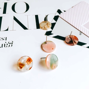 Detail of round acetate earring studs featuring colorful marble and tortoiseshell patterns